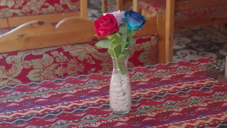 a vase of artificial roses on a patterned table in a restaurant