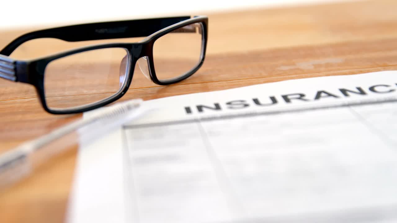 Close-up of insurance contract, pen and spectacle