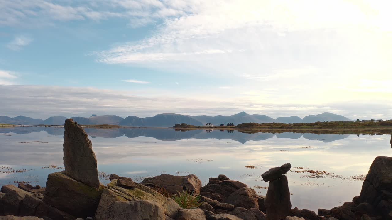 Tranquil water reflecting mountains and sky in Vestarelen, Norway, on a calm day