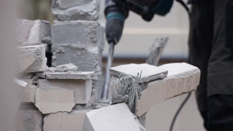 Unrecognizable-Man-Using-Jackhammer-to-Demolish-Brick-Wall---close-up-slow-motion