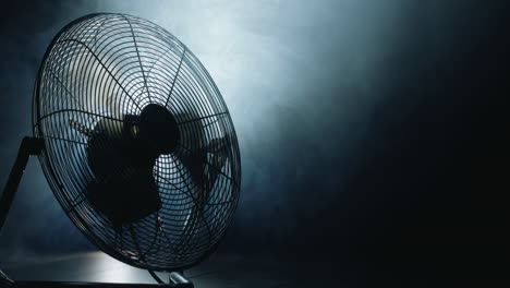 fan blades rotate in rays of light and fog. close-up shot