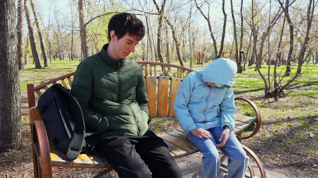 Young Man and Child Sitting Quietly on a Park Bench