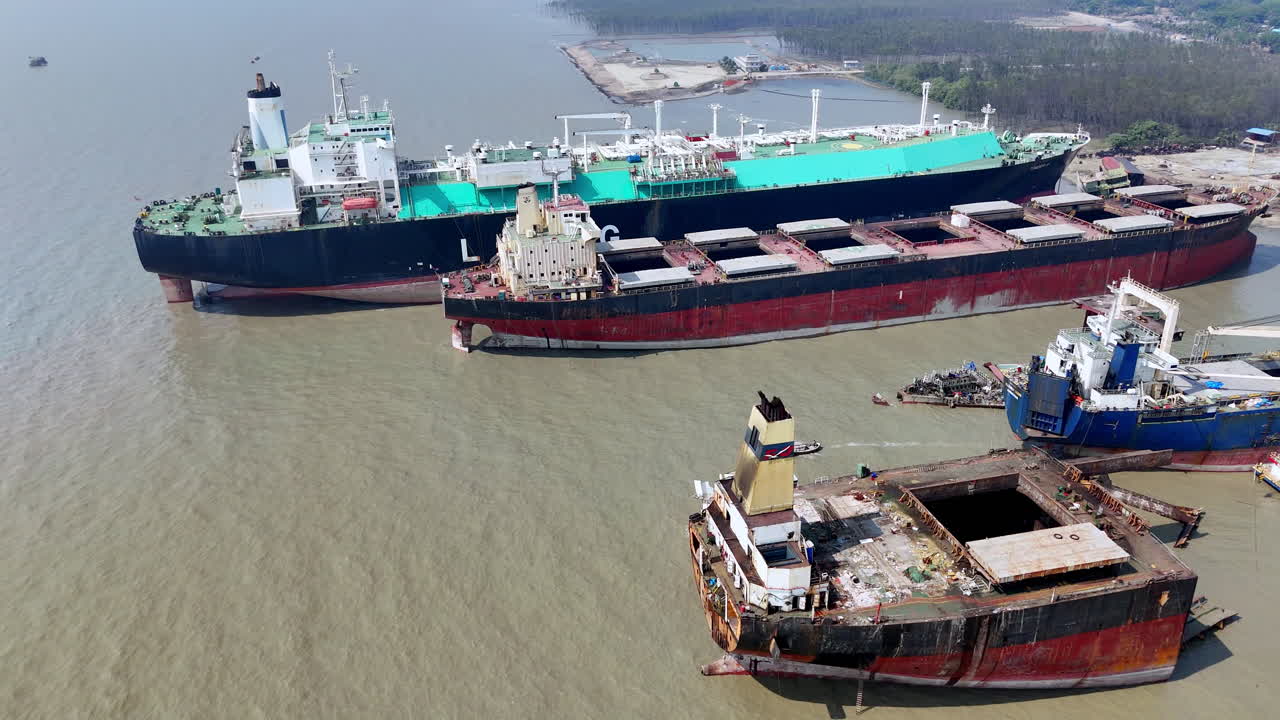 Cinematic aerial panning revealing shot of large cargo ships abandoned in a ship graveyard in Bangladesh