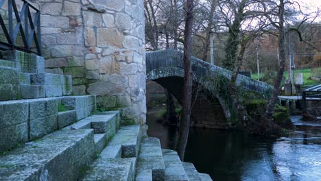 precisos escalones de granito de piedra tallada conducen al río molgas con puente arqueado romano