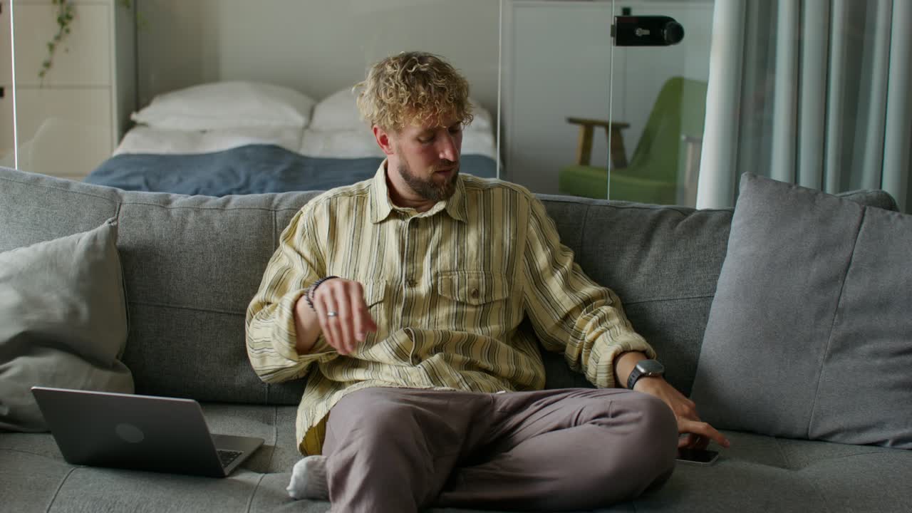 мужчина использует смартфон на диване дома