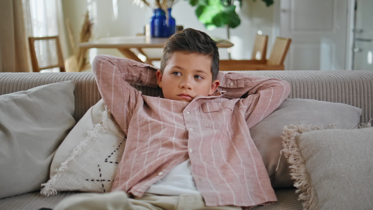 Little boy watching cartoons on tv sitting couch at living room. Kid resting