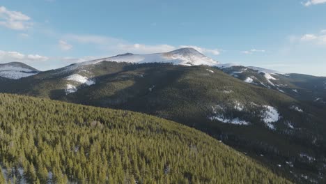 featuring of snow covered mountain peaks in the rocky mountains with green pine trees in colorado, usa. drone shot.