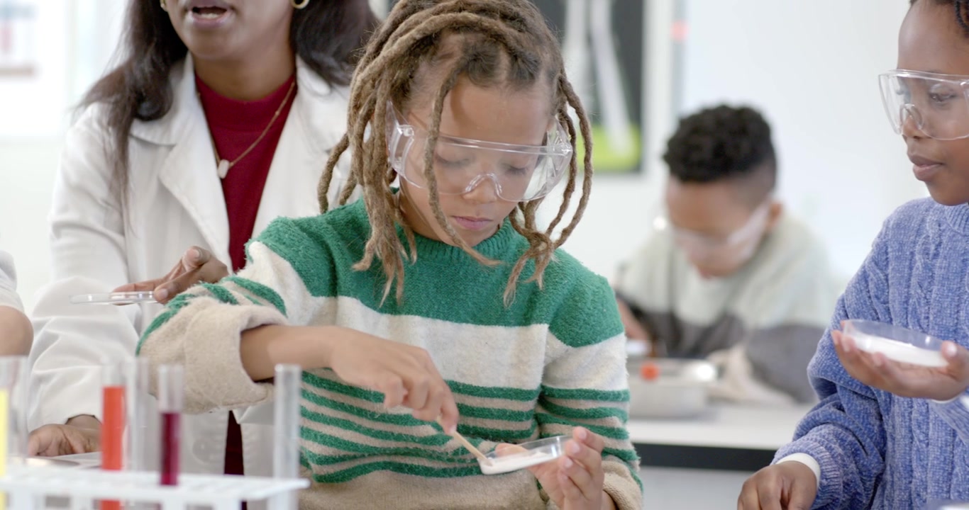 Lab class following teacher demo, using spatula, spreading powder in petri dishes at lab bench