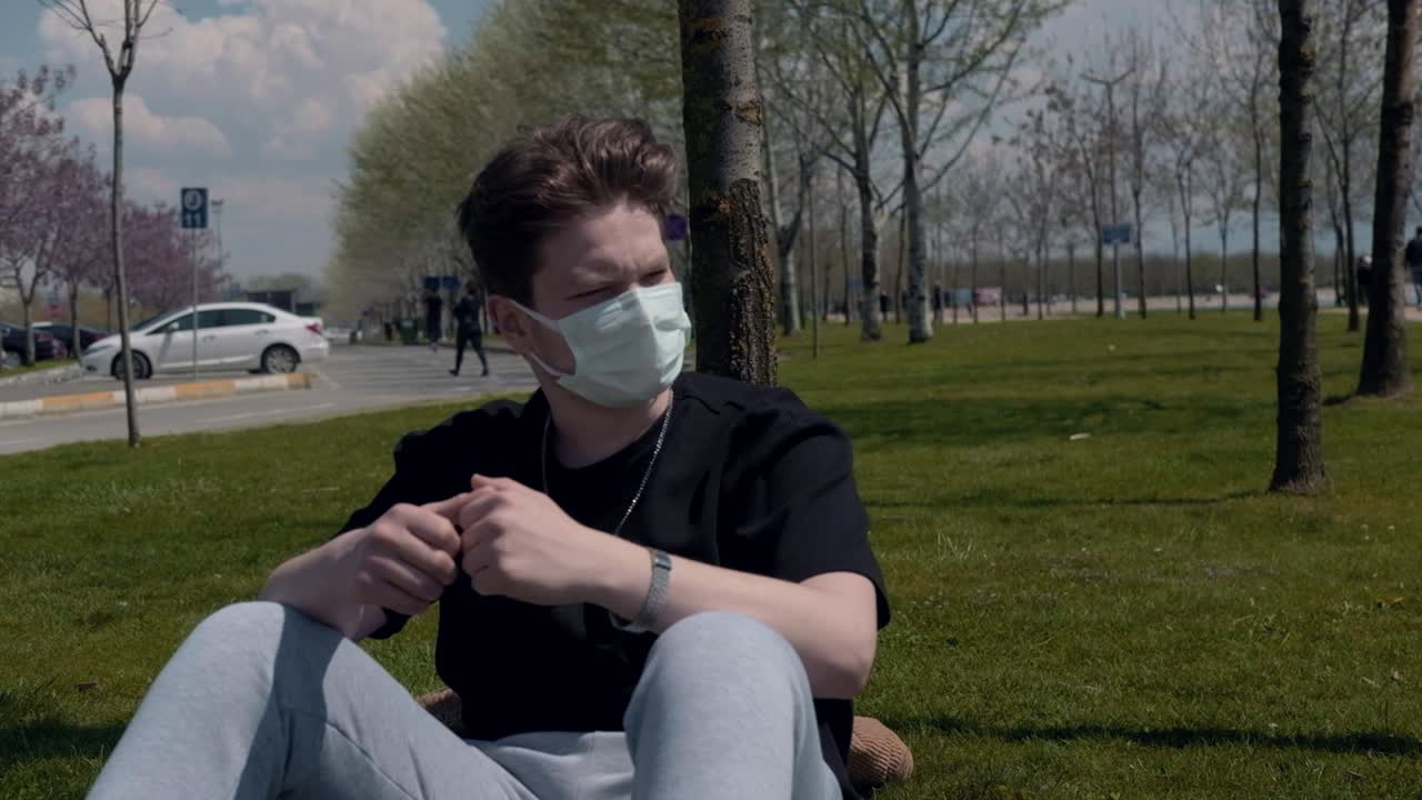 молодой человек сидит в маске.