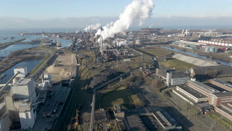 Aerial overview of large steel mill with smoking chimneys