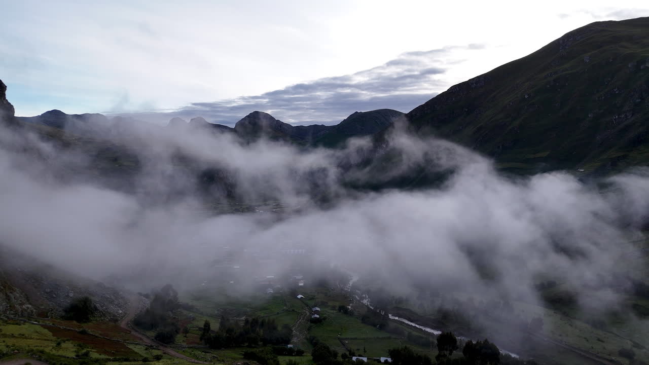 Cinematic aerial view of snowy Andes mountains in Peru with glaciers, rocky cliffs, and hidden blue alpine lake under misty clouds, dramatic landscape and natural travel destination