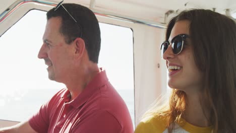 vista lateral de un hombre caucásico y su hija adolescente disfrutando del tiempo en el barco