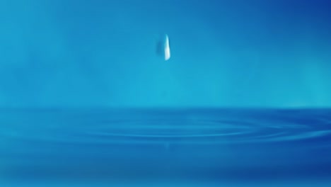 slow motion 4k video of a water surface with falling drops on a blue background. splashing water. studio shooting.
