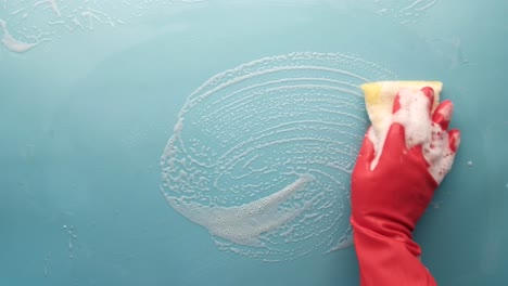 cleaning a light blue surface with a sponge and soap