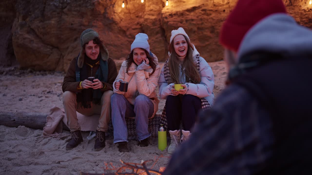 Friends enjoying a campfire at the beach in winter