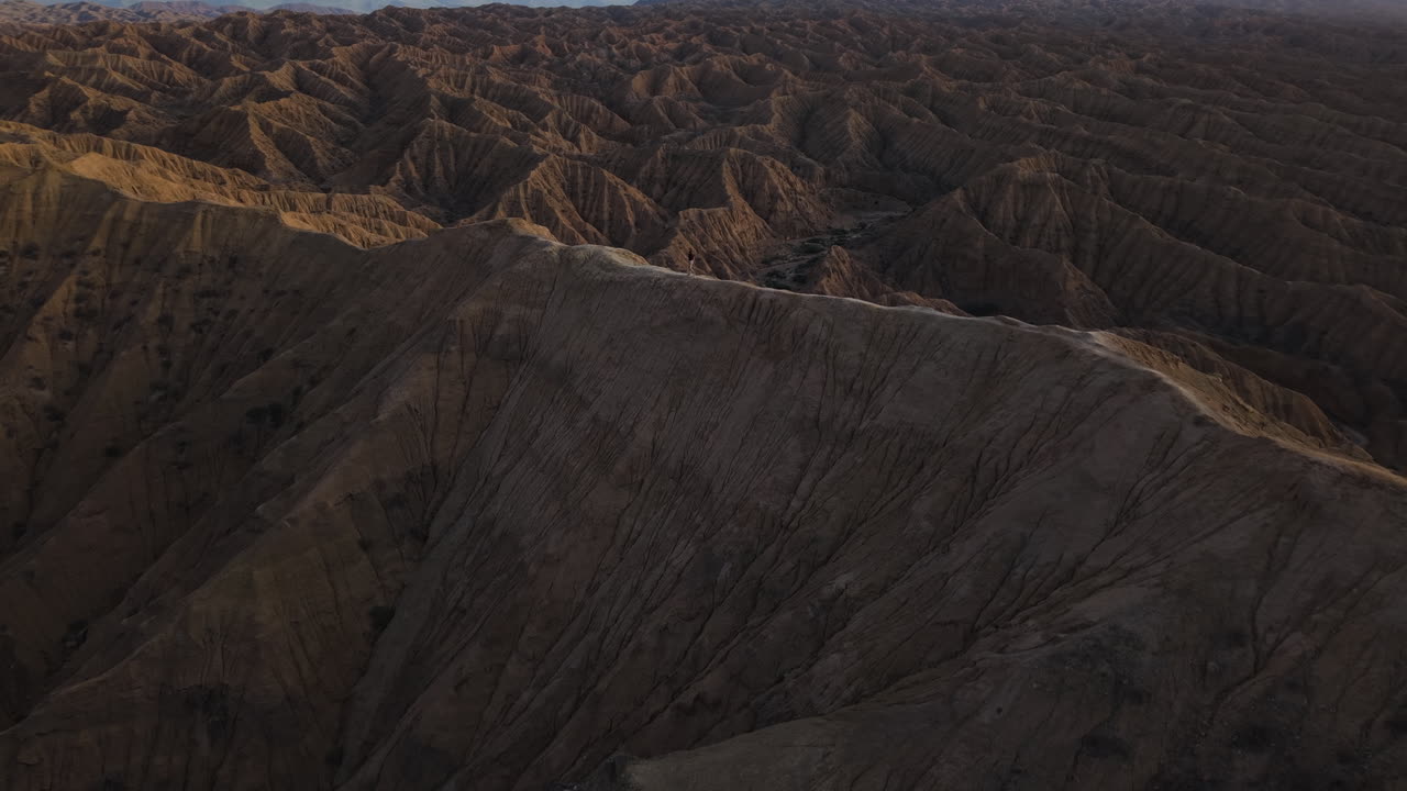 Hiker Over Dramatic Rock Formations Of The Fairytale Canyon In Kyrgyzstan, Central Asia. Aerial Pullback Shot