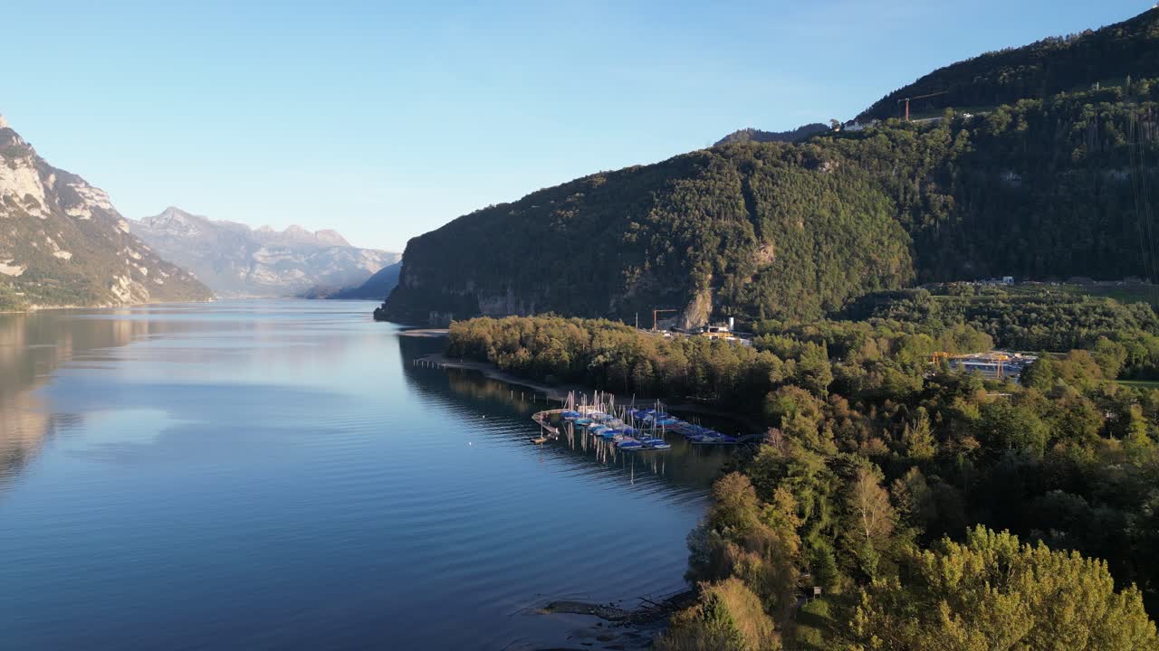 Una vista soleggiata del Lago Walensee con acqua cristallina, un piccolo porto e uno sfondo montuoso in una splendida giornata