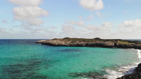 aerial drone shot of a rocky coastline starkly contrasting with brilliant blue water of the mediterranean crashing onto the rocks of majorca