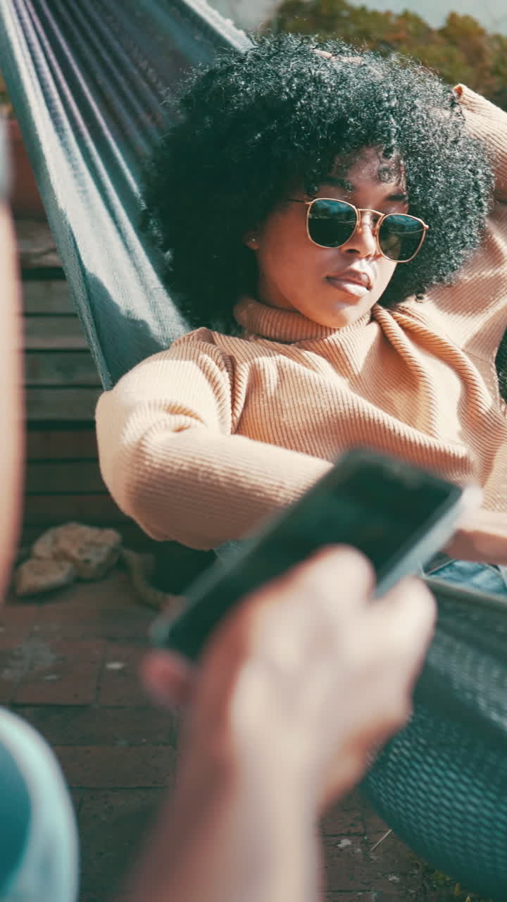 Giovane donna con capelli afro che si rilassa su un'amaca all'aperto