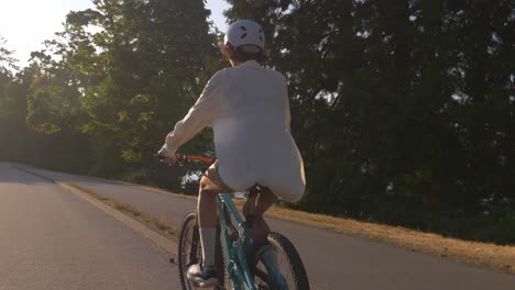 biker in helmet riding bicycle in the park during sunset