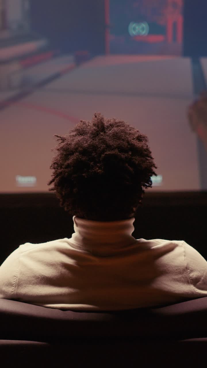 Vertical video Man playing singleplayer videogames on widescreen TV, relaxing after long day at work