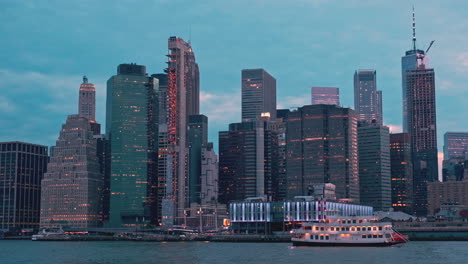 view over east river of lower manhattan skyscrapers illuminated at twilight