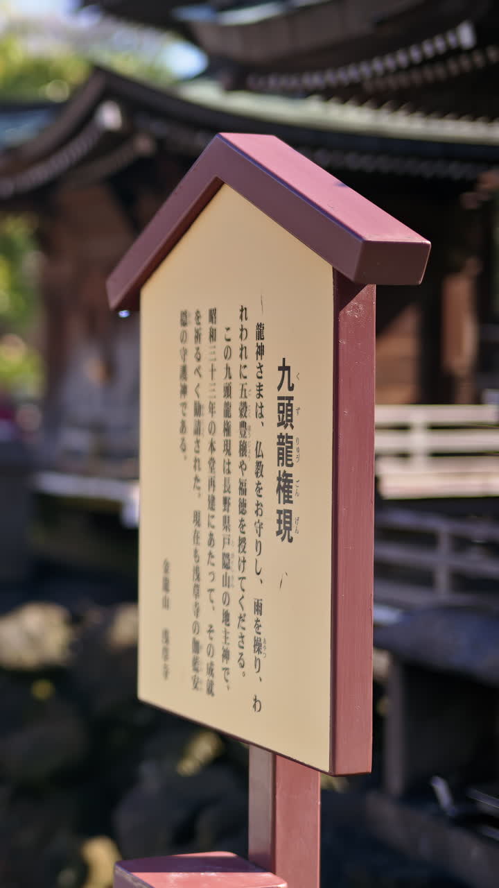 Close up of a wooden informational sign with a blurred background at the Senso-ji temple in Asakusa, Tokyo, Japan. Vertical. Translation: "information about the Mitsumine Shrine"