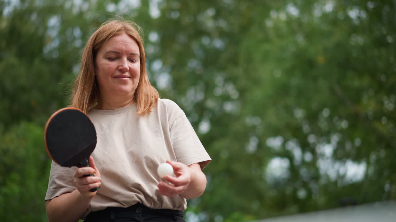 Kvinde holder en rolig pause efter spil, fredfyldt øjeblik hvor kvinde reflekterer efter konkurrencepræget bordtennis, rolig kvindelig spiller tager en stille pause for at reflektere efter at have deltaget i bordtenniskonkurrence