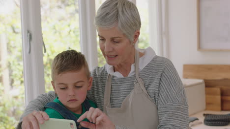 happy little boy showing grandmother how to use smartphone teaching granny modern technology intelligent child helping grandma with mobile phone at home