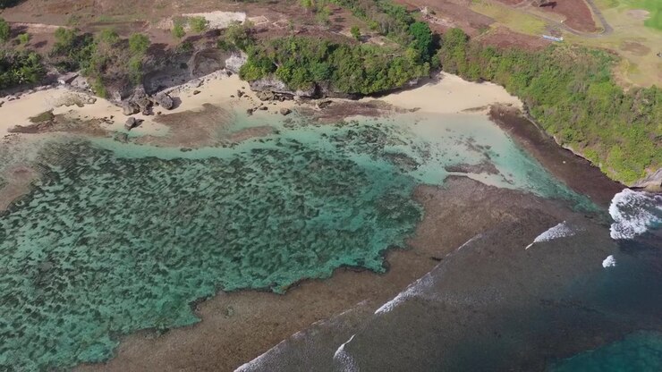 Biu Biu Beach presenta limpide rive sabbiose, acqua turchese, scogliere rocciose e onde leggere che si muovono verso la costa a Jimbaran, Bali, Indonesia