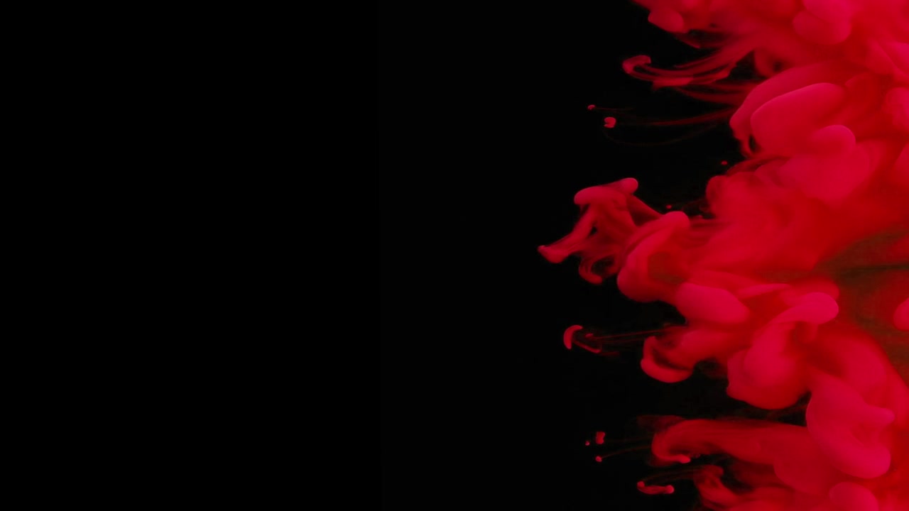 Inchiostro rosso che turbina nell'acqua su sfondo nero