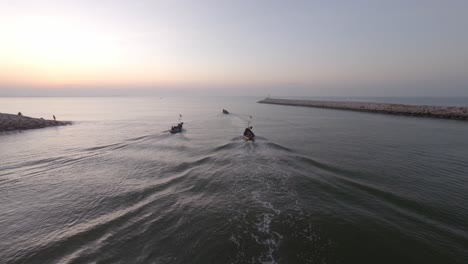 antena: tiro inclinado hacia arriba de los barcos de pescadores que nadan en el océano abierto para pescar algunos peces durante el amanecer