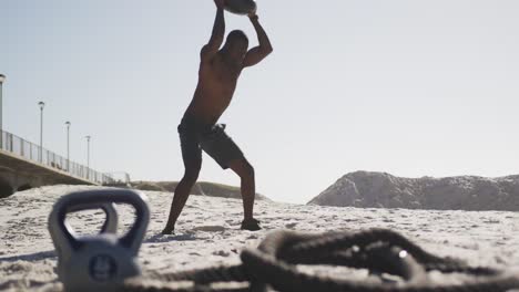 Hombre-Afroamericano-Trabajando-Con-Un-Balón-Medicinal-En-La-Playa.