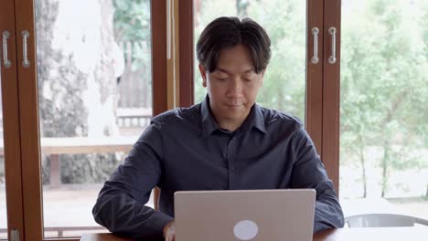 asian man working on computer in cafe