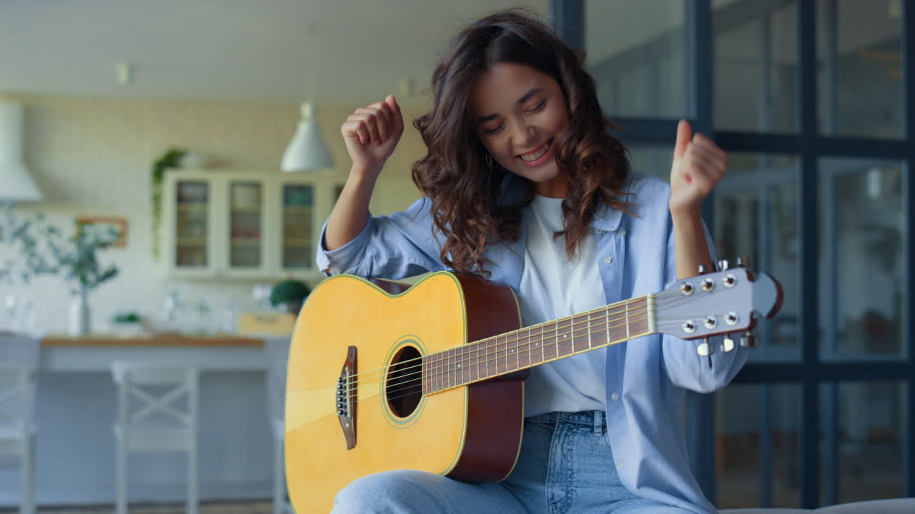Ragazza che suona la chitarra a casa. Donna felice che si esercita con la musica su uno strumento a corda.