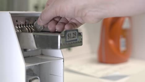 cerca de la mano está añadiendo monedas a la máquina secadora