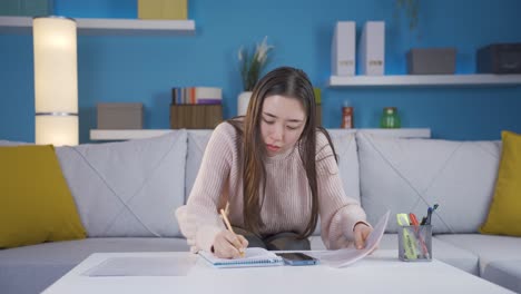 asian young woman doing calculation in her home office.