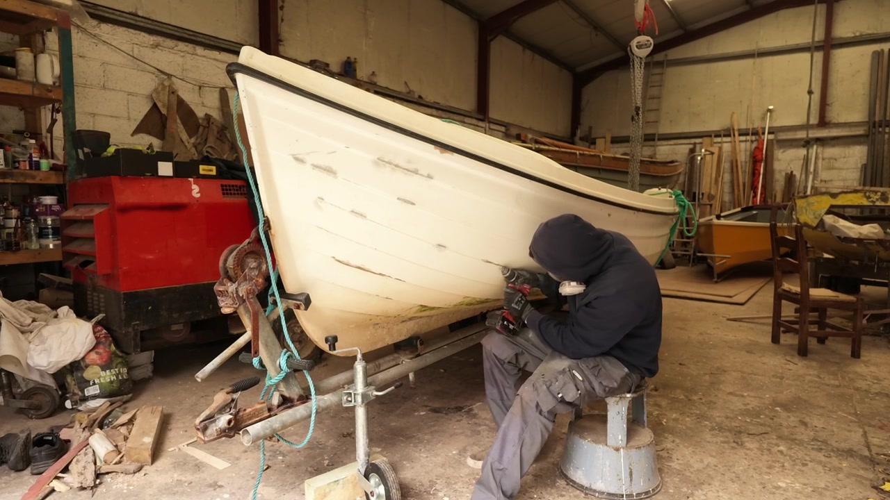 Man repairing gelcoat damage on fiberglass fishing boat