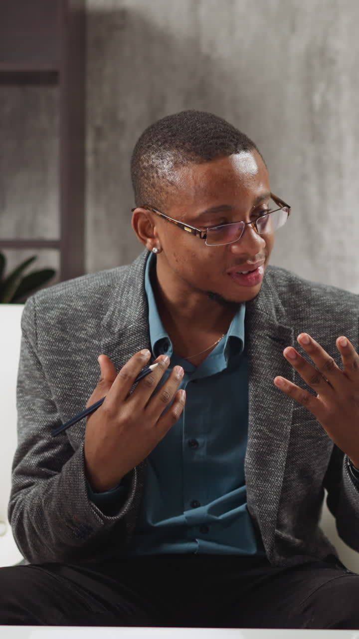 African-American teacher explains topic while bored boy yawns and little sister listens attentively during English private tuition in living room slow motion