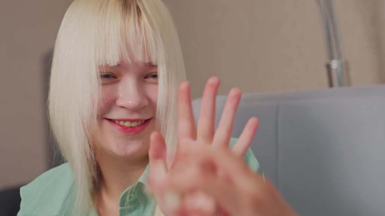 Close up of blonde girl in green shirt playfully reacting after being hit with popcorn, she covers her mouth with hand and smiles in fun interaction