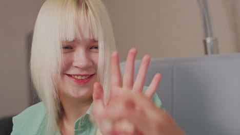 close up of blonde girl in green shirt playfully reacting after being hit with popcorn, she covers her mouth with hand and smiles in fun interaction