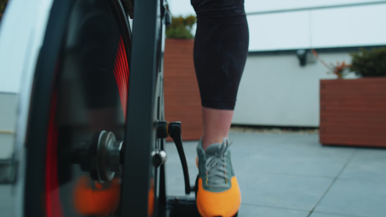 Primo piano della gamba di una ragazza che esegue esercizi di allenamento aerobico su cyclette all'aperto.