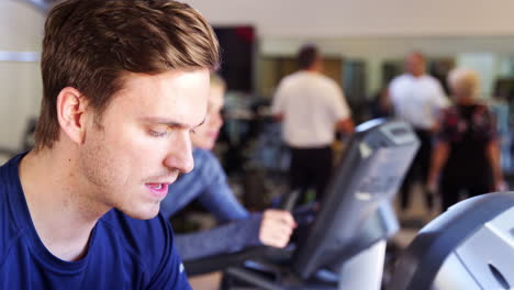 Close-Up-Of-Man-Exercising-On-Cycling-Machine-In-Gym