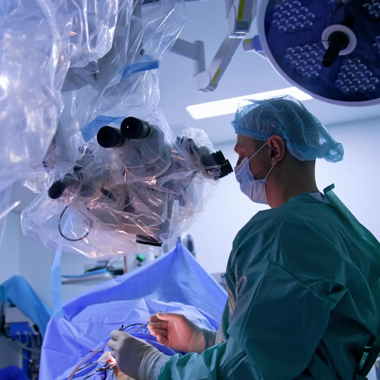 Modern surgical operation involving hi-tech equipment. Surgeon looks at microscope carrying out the procedure