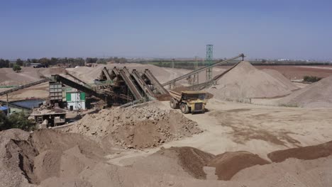 un gran camión cargado de arena se dirige hacia el sitio de construcción, fotos aéreas del camión junto con el sitio de construcción y los materiales