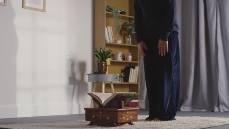 muslim woman at home sitting and reciting from the quran