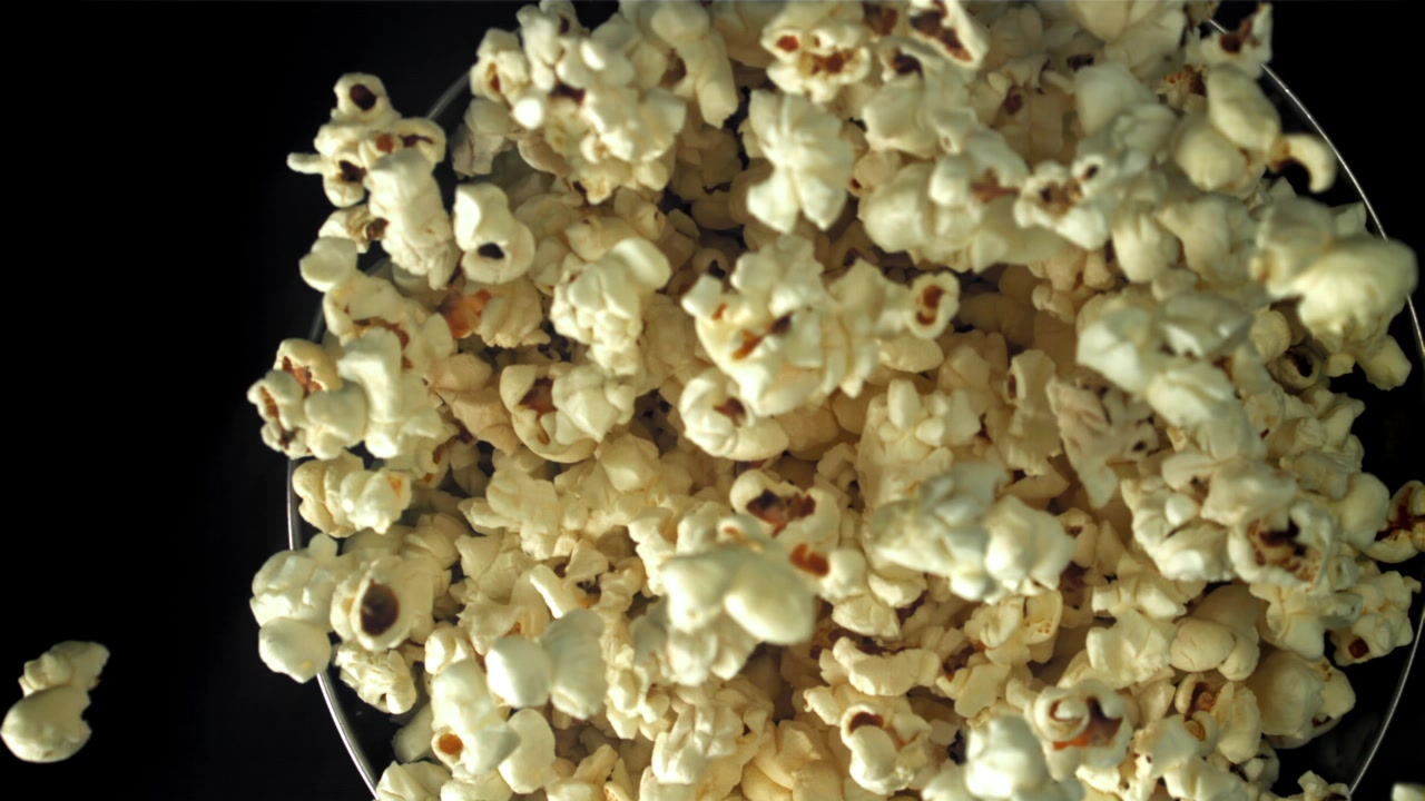 Popcorn al rallentatore che cadono in una ciotola su sfondo nero