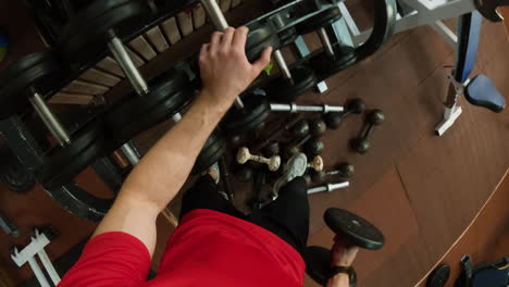 person working out in a gym with various dumbbells and weights