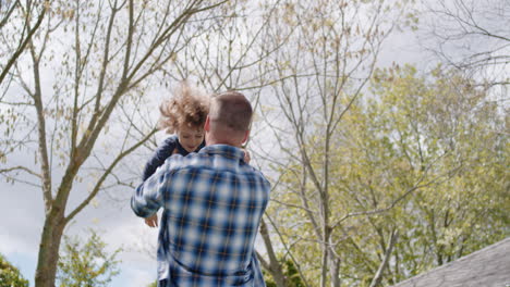 happy father and son playing together in backyard garden happy little boy having fun with dad holding child playfully swinging his kid enjoying childhood freedom outdoors 4k