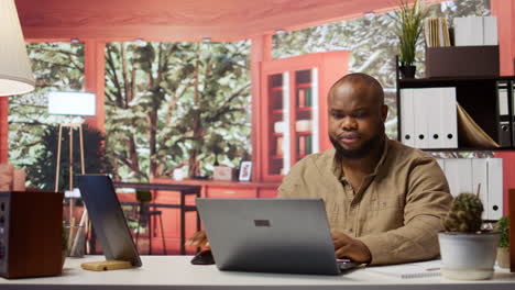 Entrepreneur-sitting-at-his-desk-working-on-laptop-with-wireless-technology